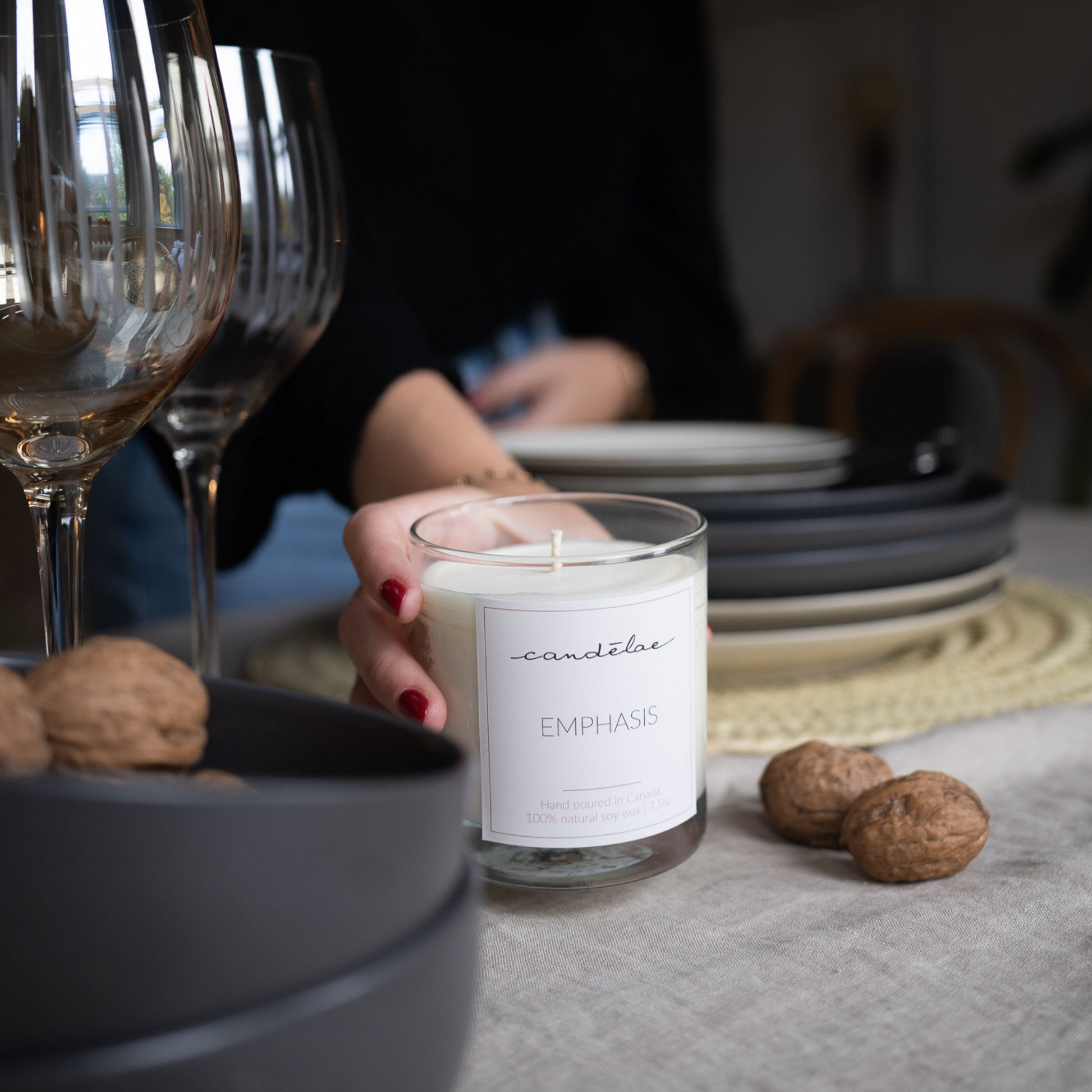 A girl is setting Emphasis scented candle on a table around nuts, bowls and plates
