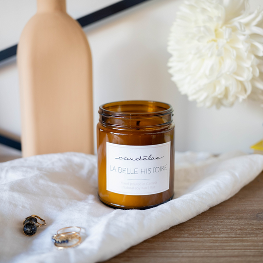 The candle from candēlae named La Belle Histoire is set as a decoration next to a beautiful vase
