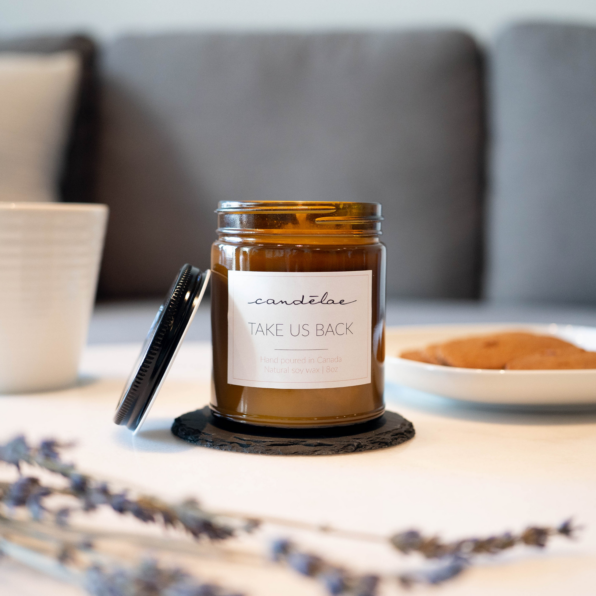 Take us back scented candle by candēlae has been put on the coffee table next to lavender